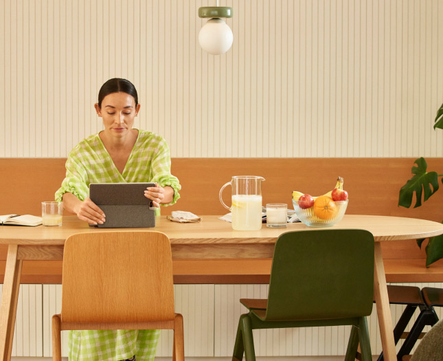 A woman in a dining room holds her tablet