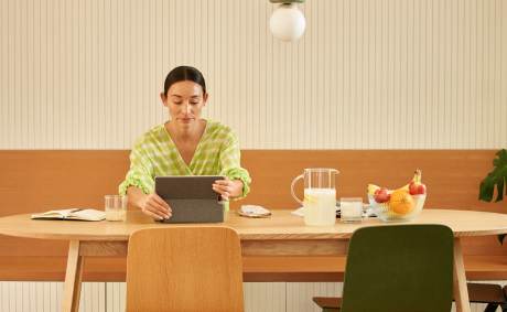 A woman in a dining room holds her tablet
