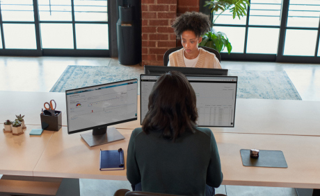 Two women working on their laptops in front of each other at the office