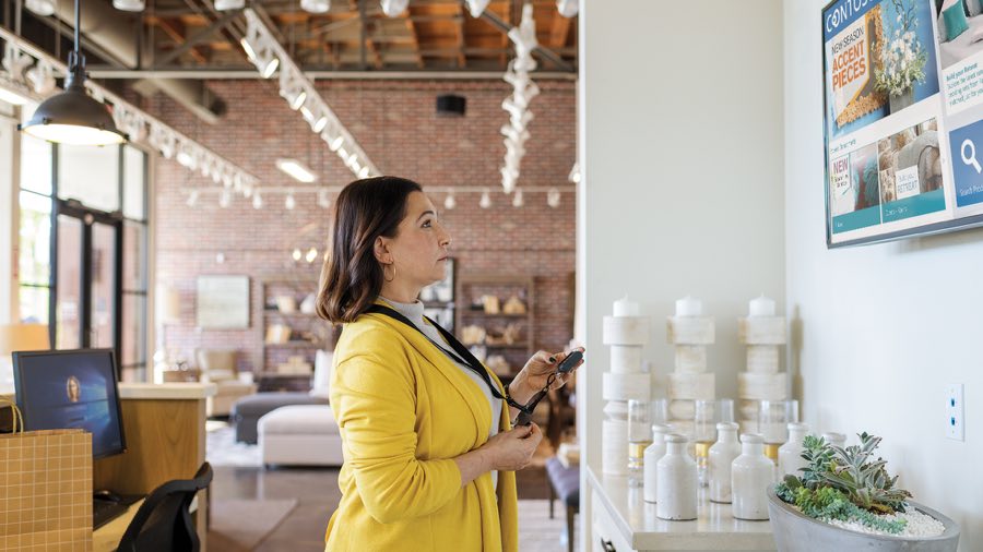 Person standing in a lobby looking at a wall mounted TV screen
