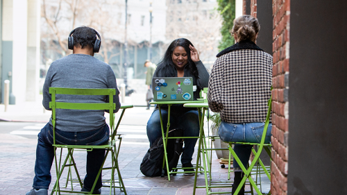 A woman working at her laptop at an outdoor table