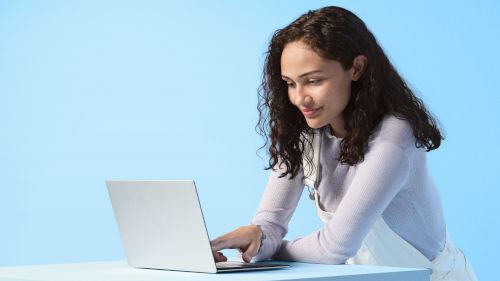 Frau am Laptop vor einem blauen Hintergrund 