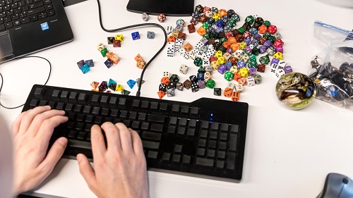 Close up of hands on a keyboard next to colorful dice