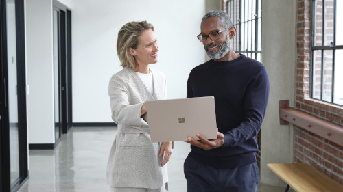 Eine Frau und ein Mann unterhalten sich und haben einen Laptop in der Hand