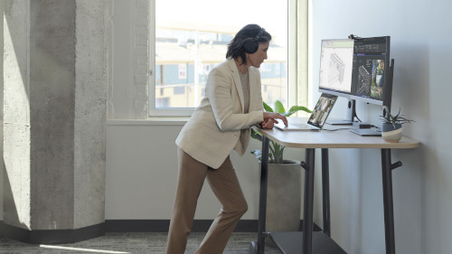 Eine Frau steht am Schreibtisch vor ihrem Computer