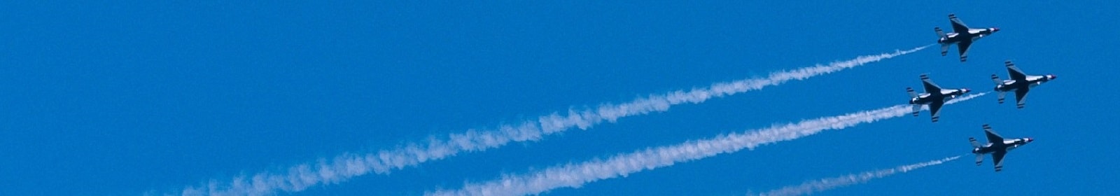 Four jets flying across a blue sky