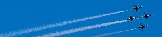Four jets flying across a blue sky