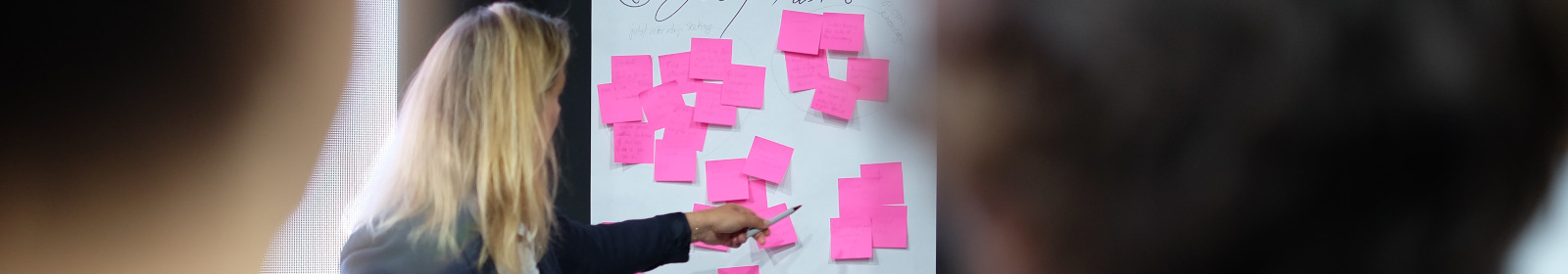 image of three people in front of a board of sticky notes
