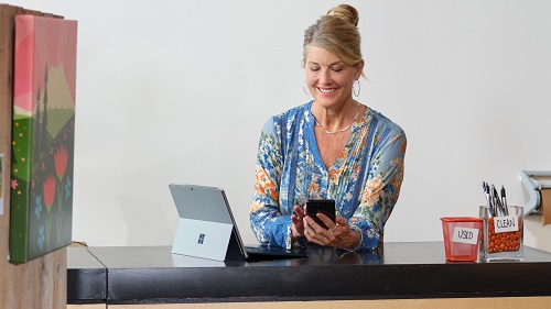 A shop owner working in her retail store using a tablet and phone