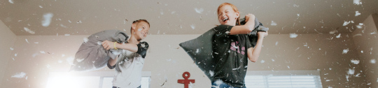 image of two children fighting playfully with pillows