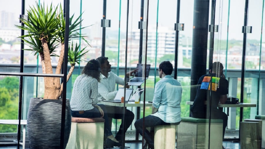 Mitarbeiter arbeiten in einem gläsernen Meetingraum am Projekt zusammen