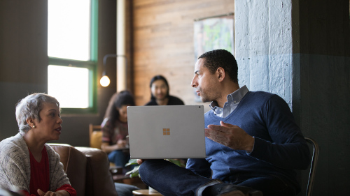 Two people in a discussion while working on a laptop