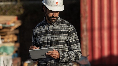 A man in a hardhat on a jobsite using a tablet