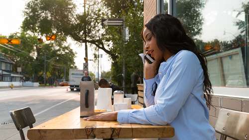 A woman on the phone at a café table outside