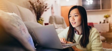 Woman smiling on a sofa working on a laptop