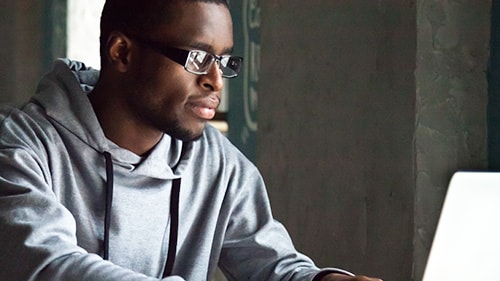 Man in grey hoodie looking at laptop