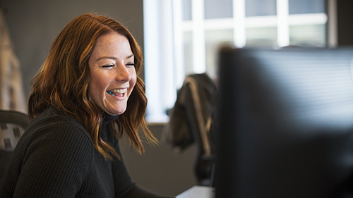 Young woman smiling while working at desktop screen