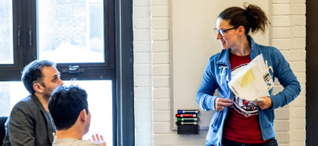 Three professionals meet near a whiteboard in the office