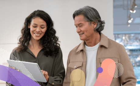 Two people smiling as they look onto a computer screen