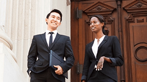 Two coworkers in black suits talking