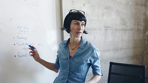 Image of a woman pointing to a white board