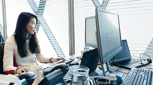 Image of woman working at desk with coffee mug