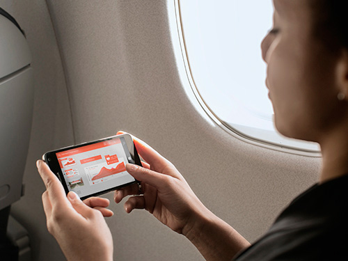 Woman traveling on plane working on cell phone