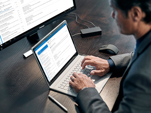  Man at desk working on laptop and desktop computer