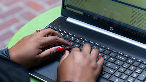Hands typing on a laptop