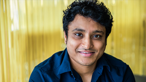 Person in front of a yellow curtain smiling
