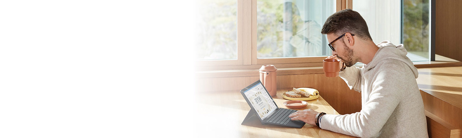 Person works on computer over breakfast in a sunny room