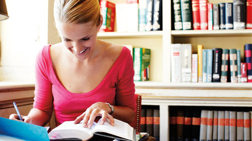 Woman looks at book and tablet