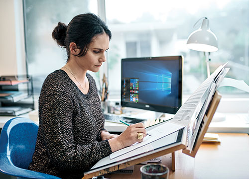 Femme en train de dessiner assise à un bureau