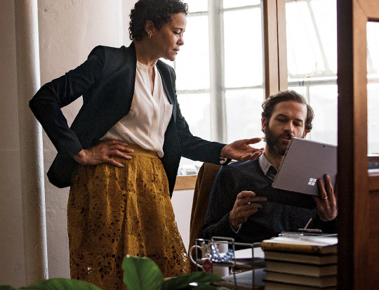 Two coworkers talking and working on Surface