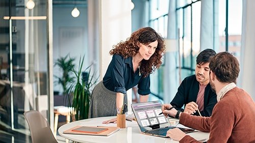 Coworkers having meeting at table working on laptop 