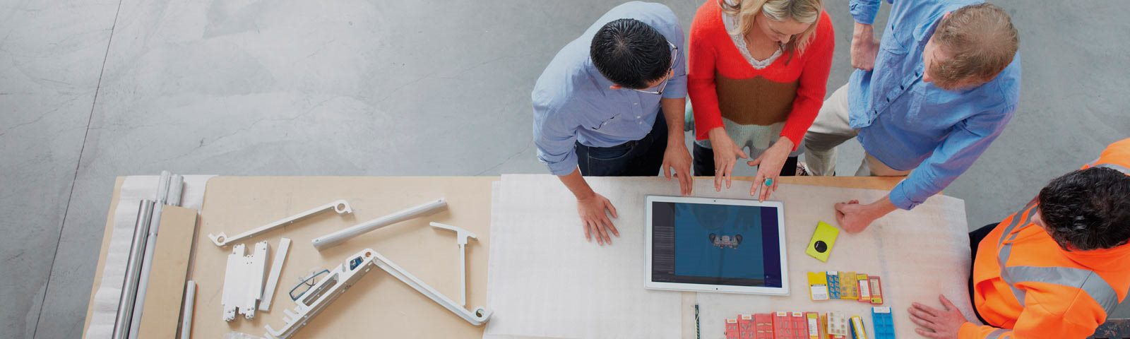 Four construction workers working on surface at desk 