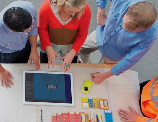 Four construction workers working on surface at desk 