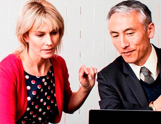 Two coworkers having a meeting working on laptop 