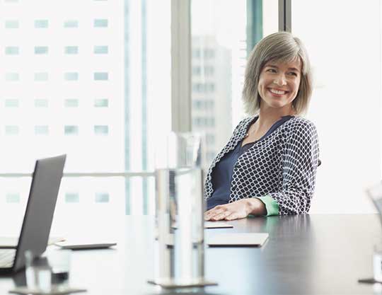 Woman smiling while sitting at conference table  