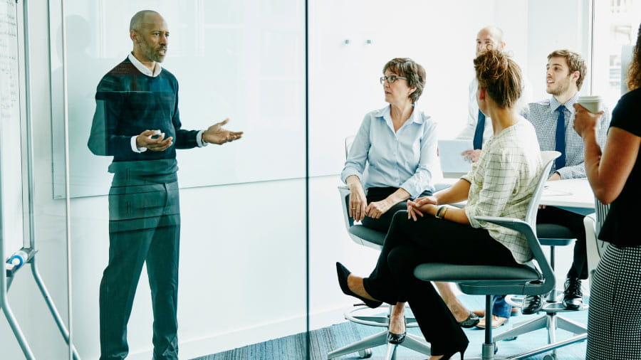 Person in black shirt presenting to a group of coworkers