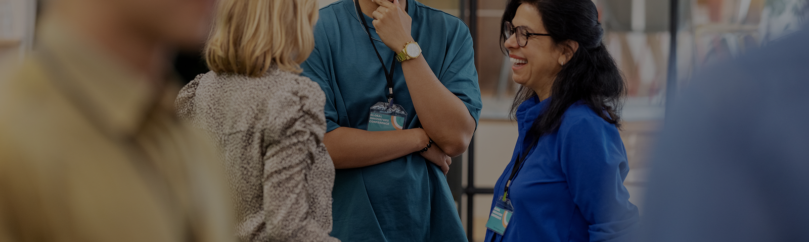 Three coworkers converse and laugh at a business conference.