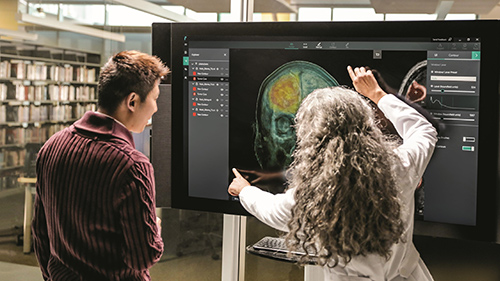 Two women standing in front of large screen