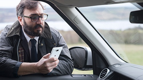 Person leaning in driver's side window with phone