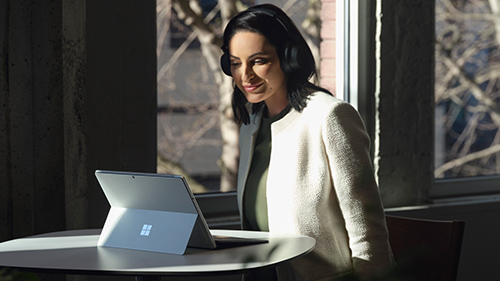 Women with headphones on Surface Pro 8