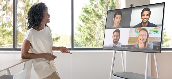 Person talking to four coworkers via Teams on the Surface Hub screen