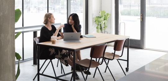 Two women talking while using Surface Book