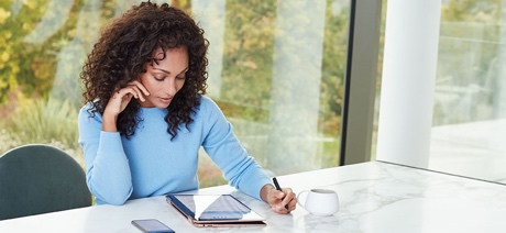 Woman sitting at a table looking down at a tablet