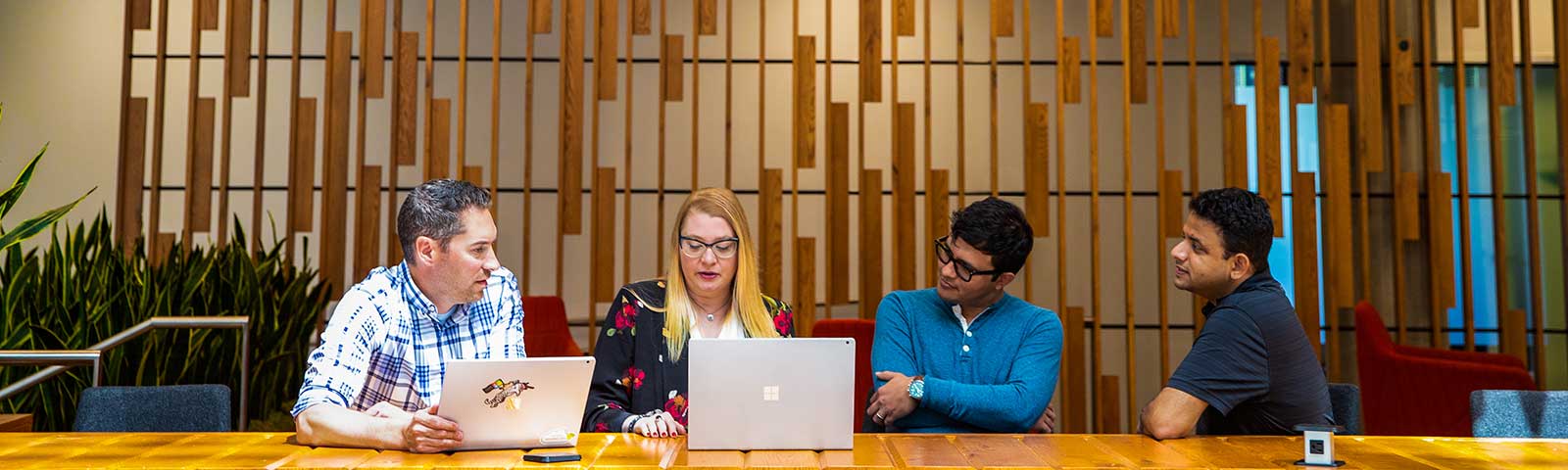 4 people sat in an office environment chatting