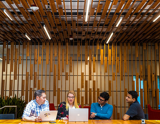 4 people sat in an office environment chatting