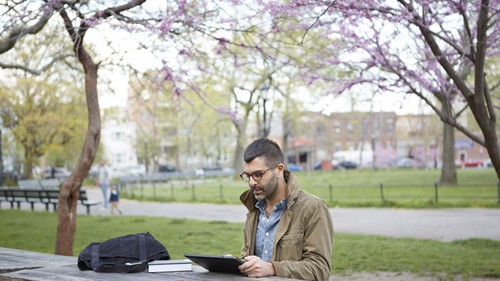 男性が外でパソコンを眺めている様子の写真です。
